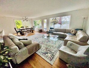 Ein Wohnzimmer mit einer Sofagarnitur, einem Couchtisch und einem Essbereich mit Stühlen und Tisch.