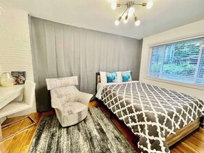 Un dormitorio con cama, una silla, un escritorio y una ventana con persianas.