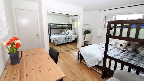 Ein kleines Zimmer mit einem Holztisch, einem Etagenbett und einem Schreibtisch mit Stuhl.
