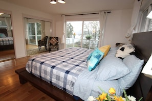 A bedroom with a large bed, a bench, a chair, and a view of the outdoors. - Luxury 180 degree Lake View N Mercer Island Home 1 (Mercer Island)