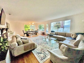 A spacious living room with a large window, a glass coffee table, and a sofa set. - Luxury 180 degree Lake View N Mercer Island Home 1 (Mercer Island)