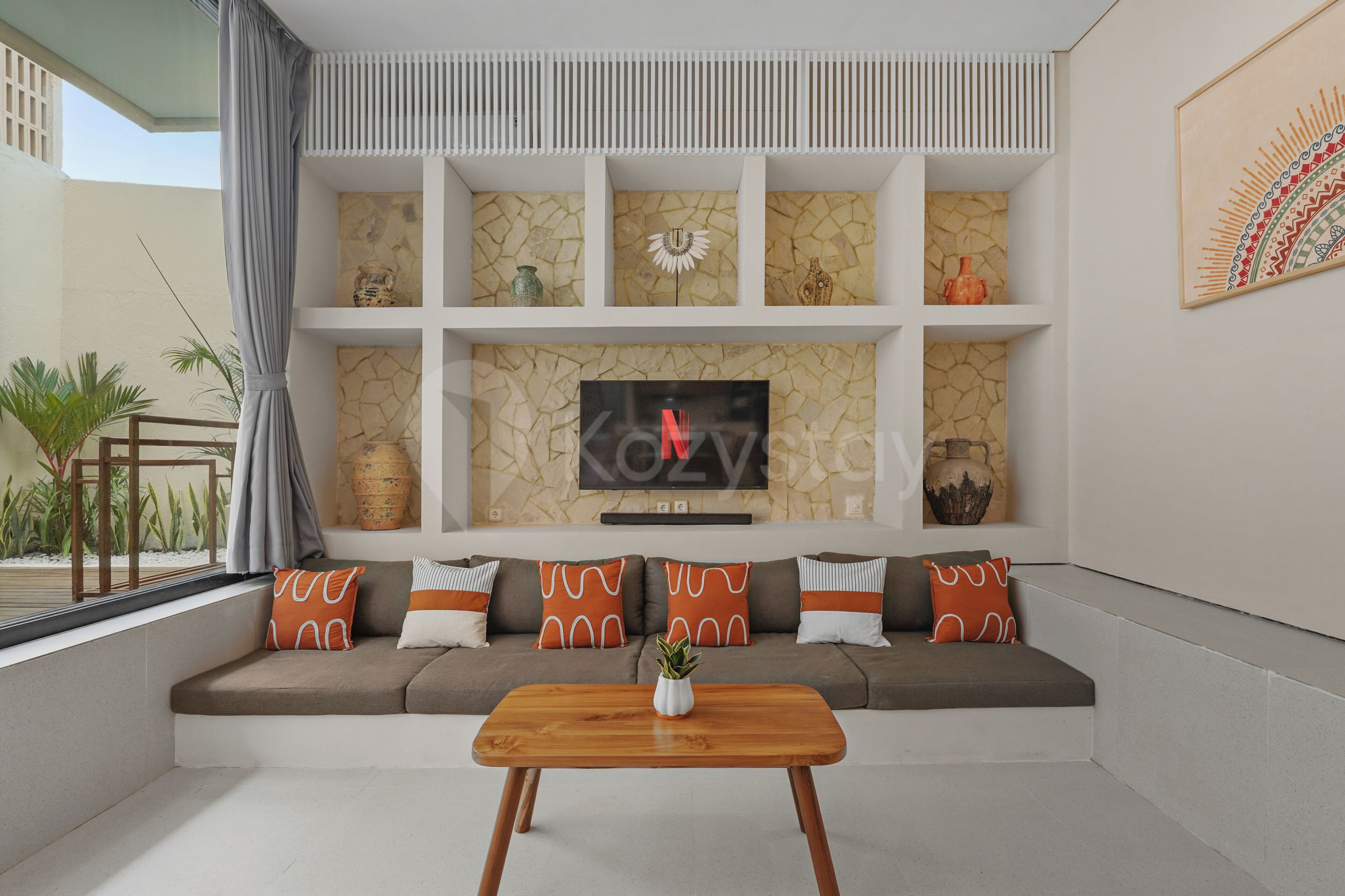 A modern living room with a sectional sofa, a flat-screen TV, decorative vases, and a wooden coffee table.