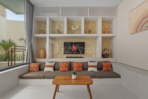 A modern living room with a sectional sofa, a flat-screen TV, decorative vases, and a wooden coffee table.