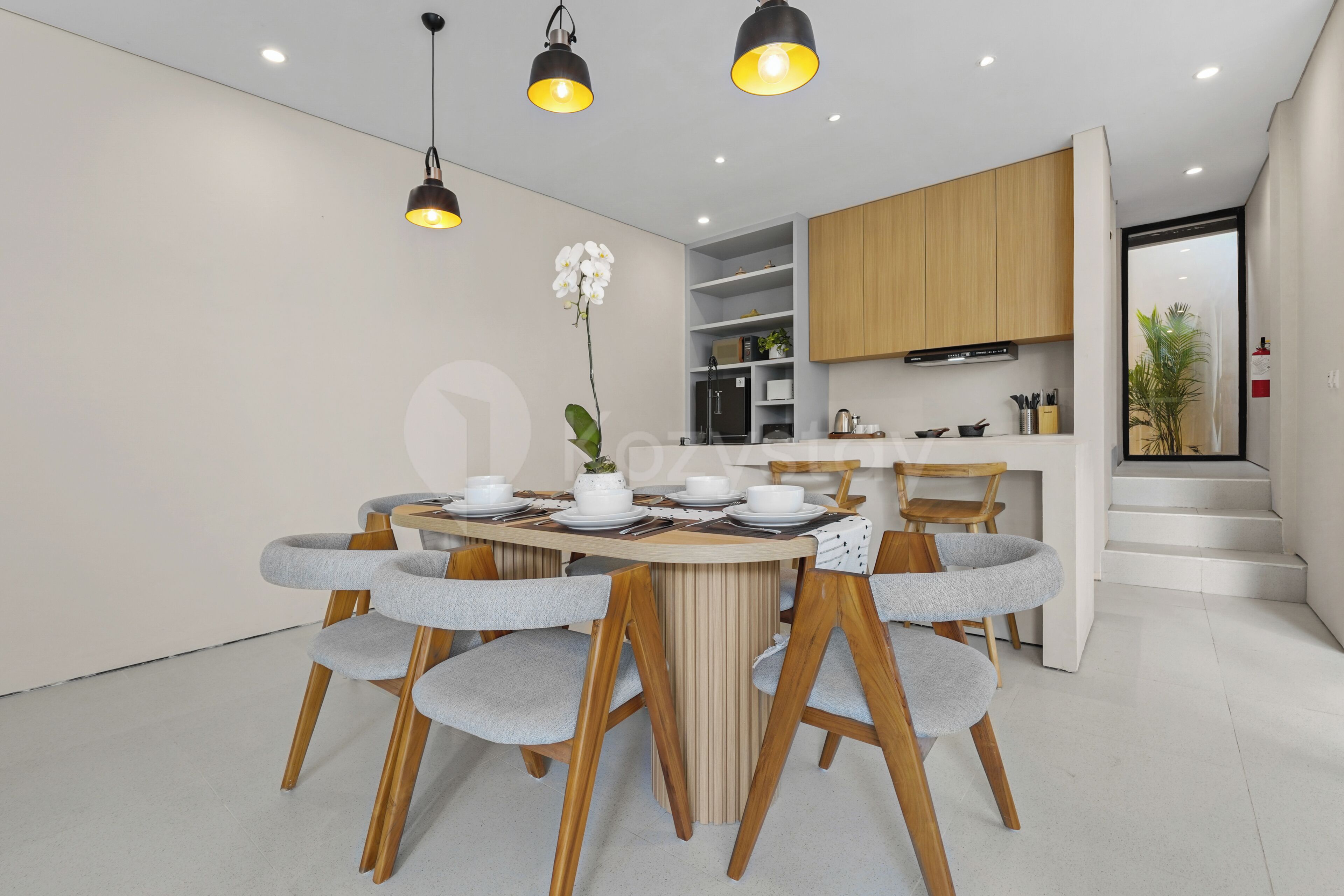 A modern dining area with a round table, chairs, and pendant lighting.
