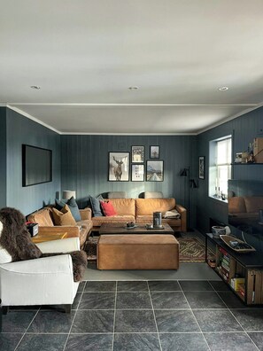 A modern living room with a sectional sofa, a coffee table, and a fireplace.