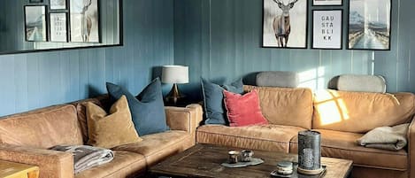 Ein Wohnzimmer mit einer Eckcouch, einem Couchtisch und einem gemusterten Teppich.