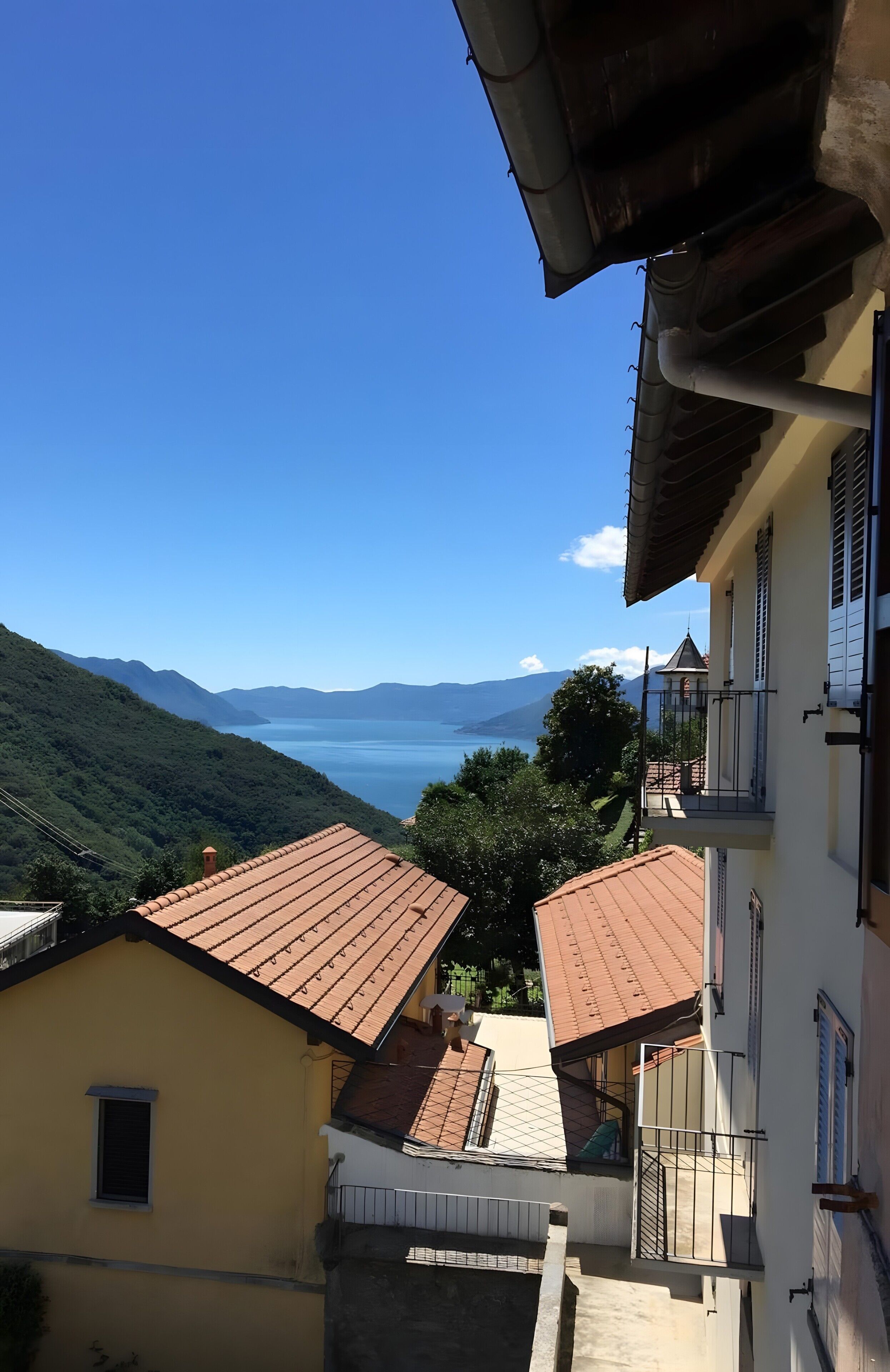 A residential area with terraced houses, a clear blue sky, and a distant view of a body of water.