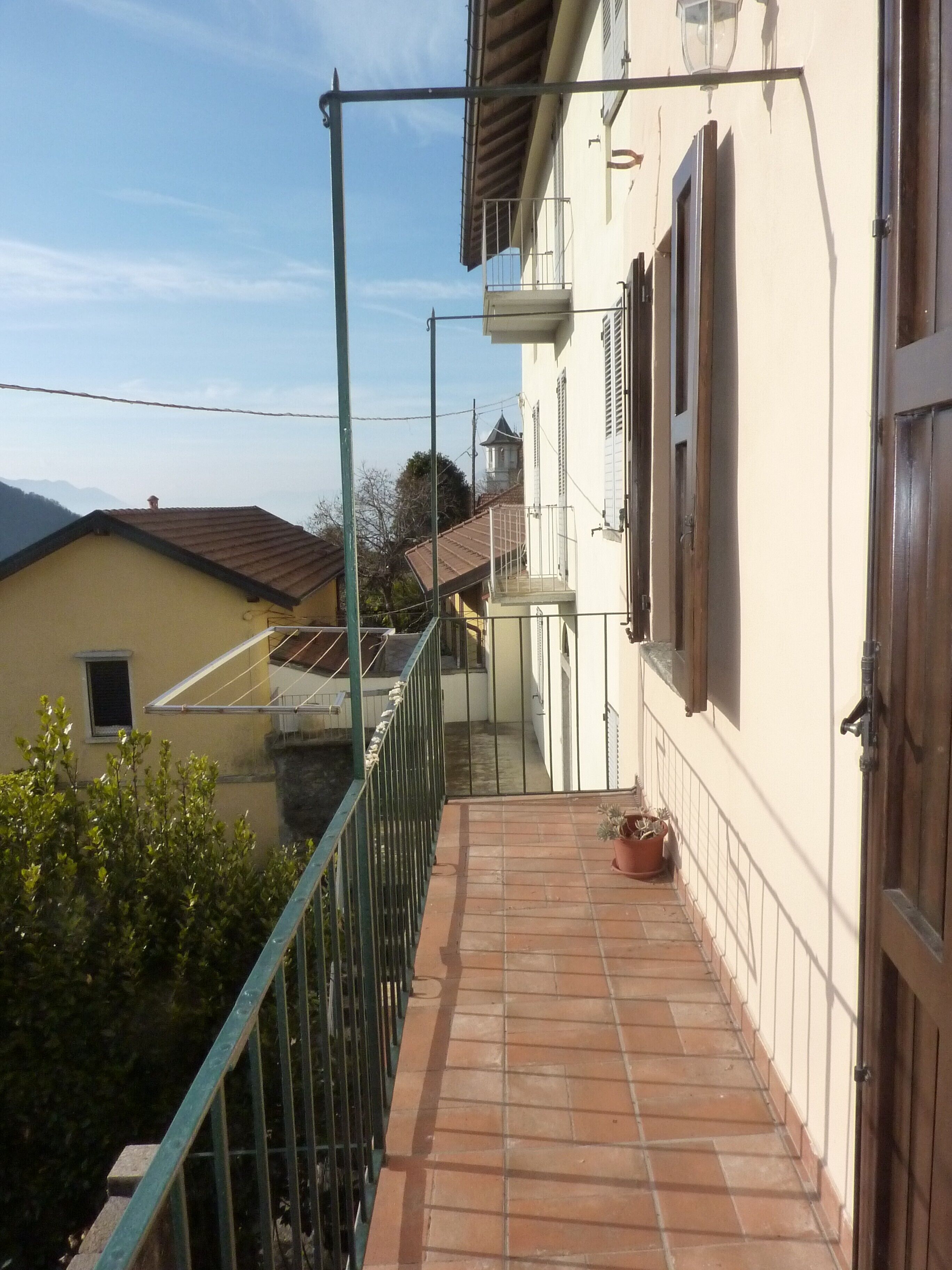 Ein Balkon mit Fliesenboden, Metallgeländer und einem Blumentopf.