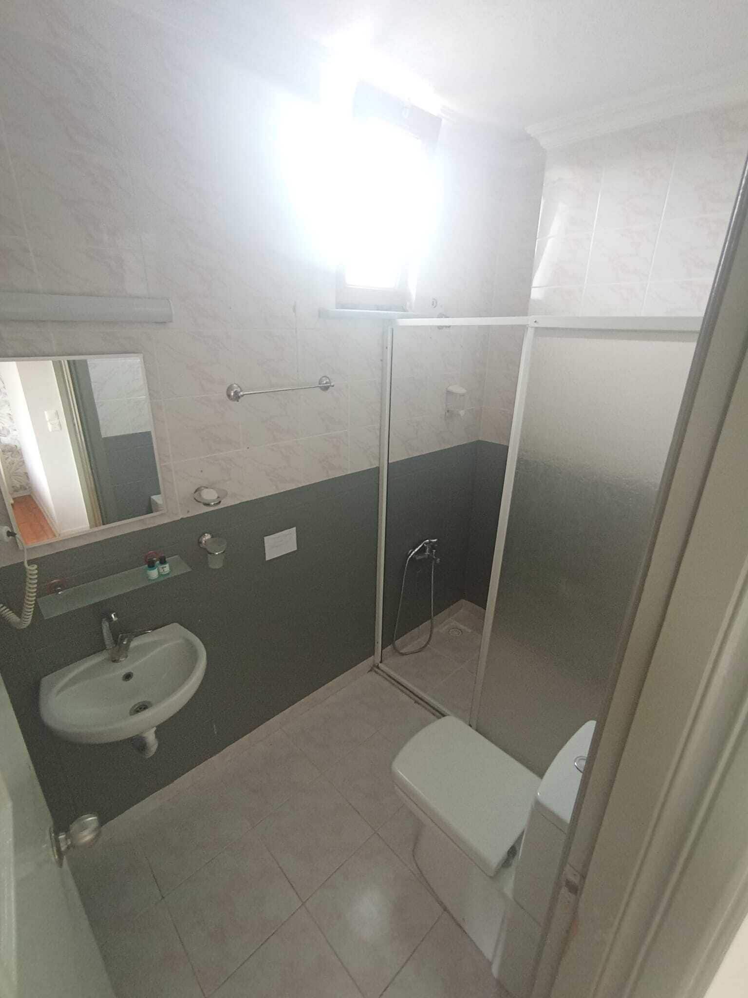 A bathroom with a sink, mirror, and shower enclosure.