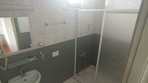 Et badeværelse med vask, spejl og brusekabine.