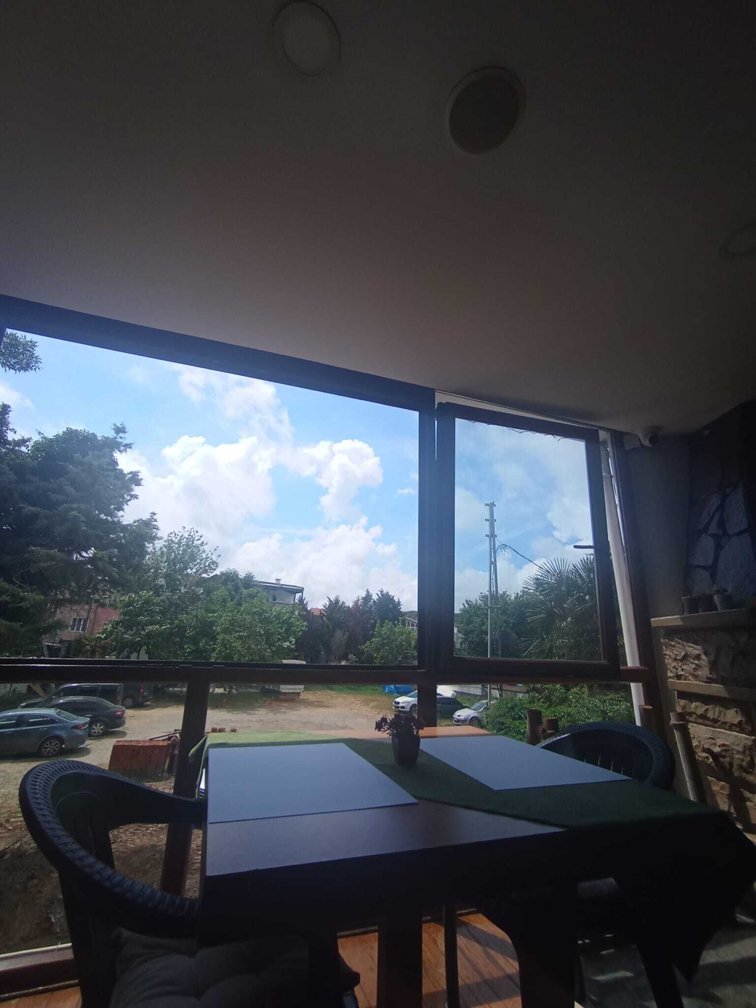 A room with a large window, a table, and chairs.