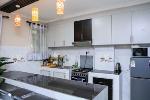 A modern kitchen with white cabinets, a stainless steel stove, and a refrigerator. - 1 Bedroom Apartment in Utawala Nairobi  Near JKIA Free Wi-Fi & Parking (Nairobi)