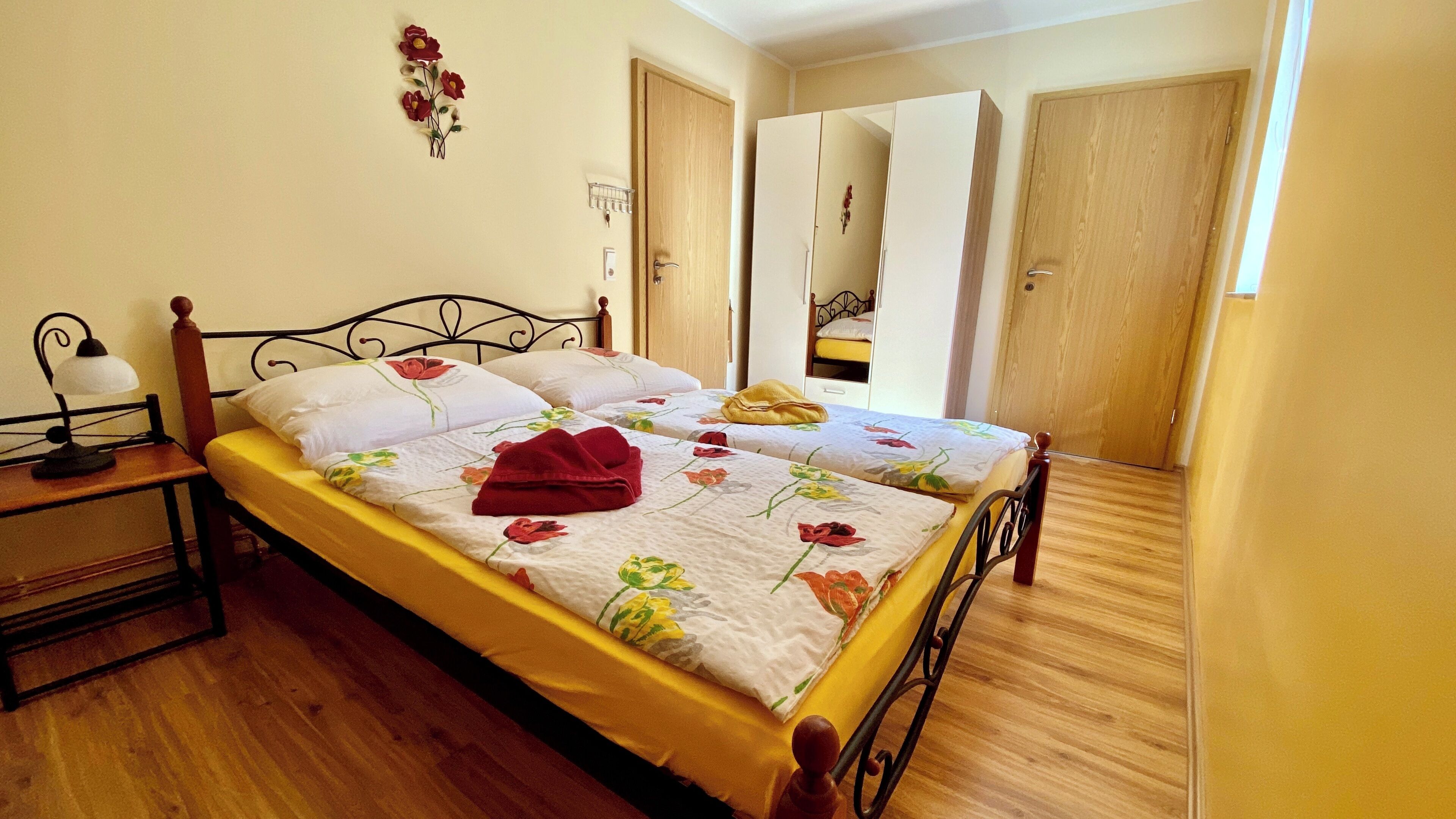 Ein Schlafzimmer mit einem Bett, einem Nachttisch, einer Lampe und einer Tür.