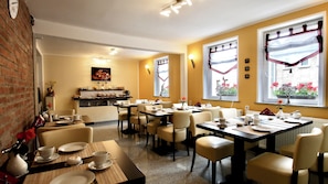A dining area with multiple tables and chairs, a buffet counter, and a view of flowers through the windows. - Vrbo Property (Eisenach)