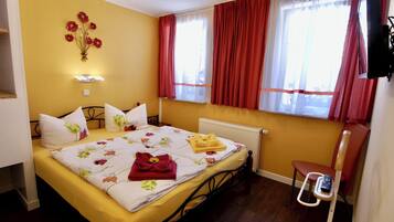Ein Hotelzimmer mit Bett, Heizkörper, Stuhl und einem fensterbepflanzten Fenster.