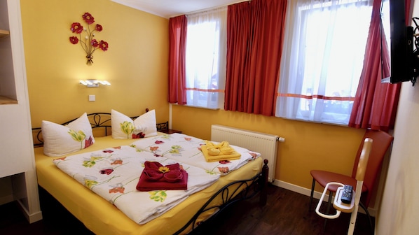 A hotel room with a bed, a radiator, a chair, and a window with curtains. - Vrbo Property (Eisenach)