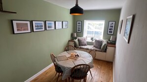 A dining area with a round table, chairs, a checkered tablecloth, and framed pictures on the wall. - Cottage - Sleeps 5 - Parking & Wood Burning Stove (Alnwick)