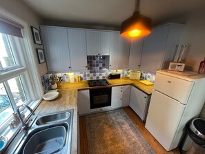 A kitchen with white cabinets, a wooden countertop, a sink, and a built-in oven. - Cottage - Sleeps 5 - Parking & Wood Burning Stove (Alnwick)