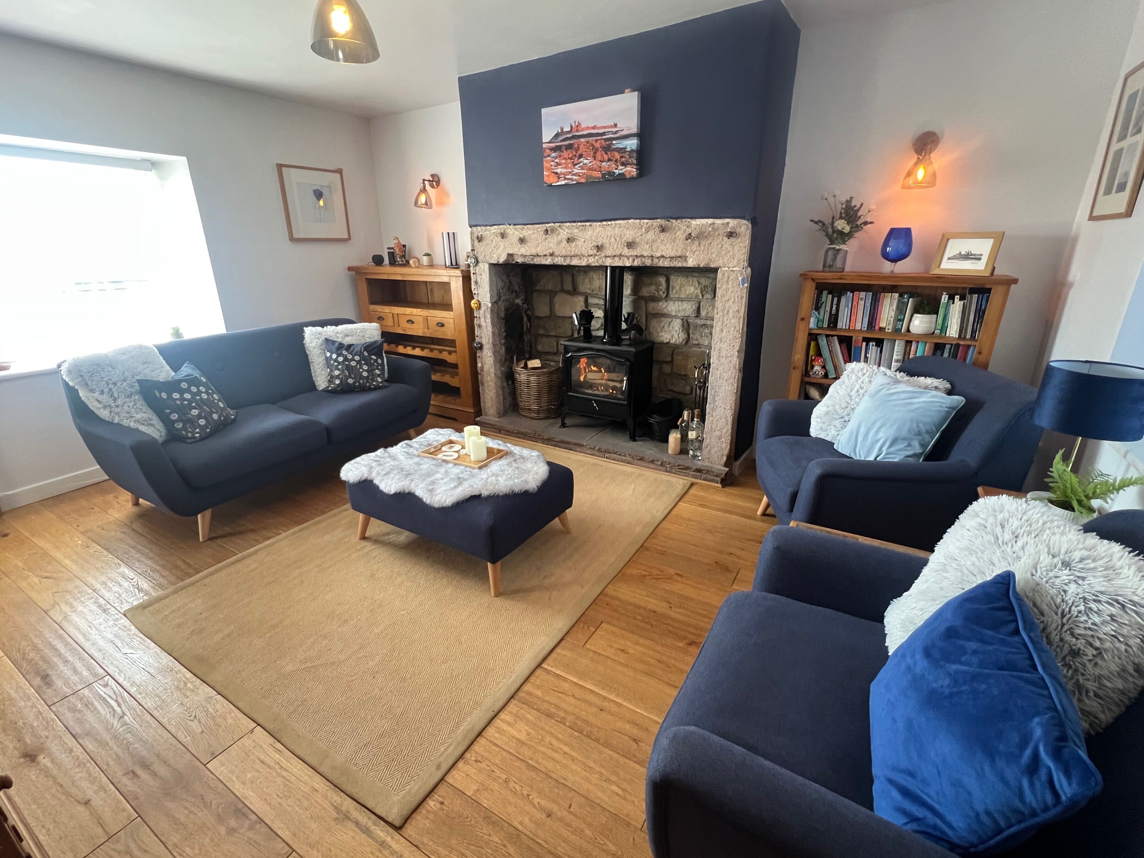 A cozy living room with a fireplace, two sofas, a coffee table, and a bookshelf.
