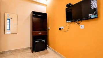A room with a television mounted on the wall, a wooden cabinet, and a small safe.