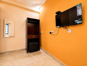 Una habitación con televisor montado en la pared, un mueble de madera y una caja fuerte pequeña.