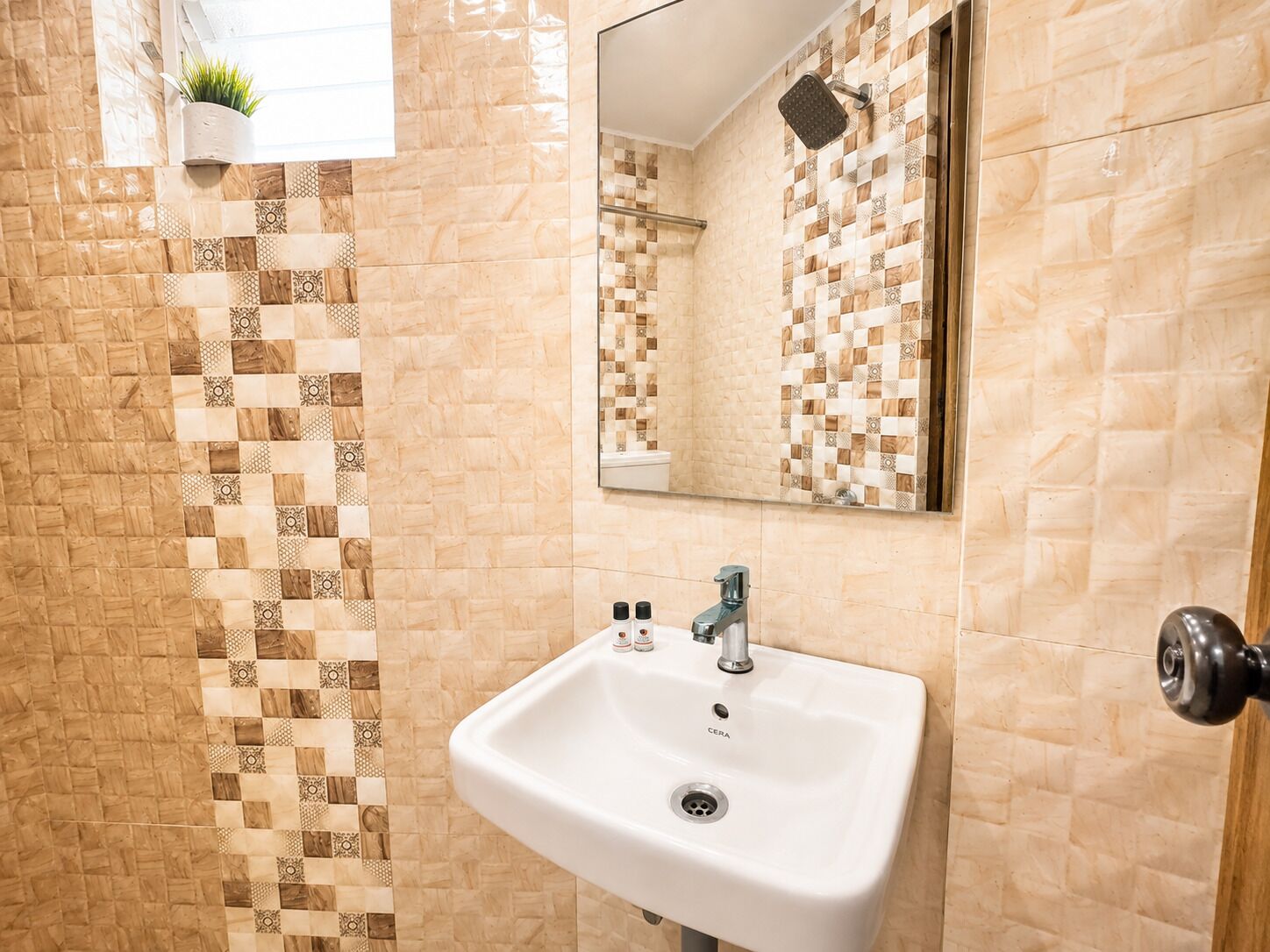 Une salle de bain avec un lavabo blanc, un miroir et des carreaux à motifs.