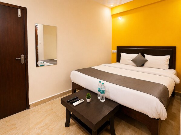 Una habitación de hotel con una cama, mesita de noche y un espejo.