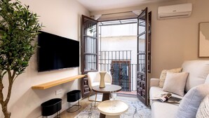 A modern living room with a flat-screen TV, a round coffee table, a sofa, and a potted plant. - Genteel Home Santa Ines (Granada)