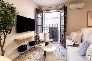 Ein modernes Wohnzimmer mit Flachbildfernseher, rundem Couchtisch, einer Couch und einer Topfpflanze.
