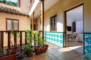 Ein Innenhof mit Topfpflanzen, einem gefliesten Boden und Blick ins Innere.