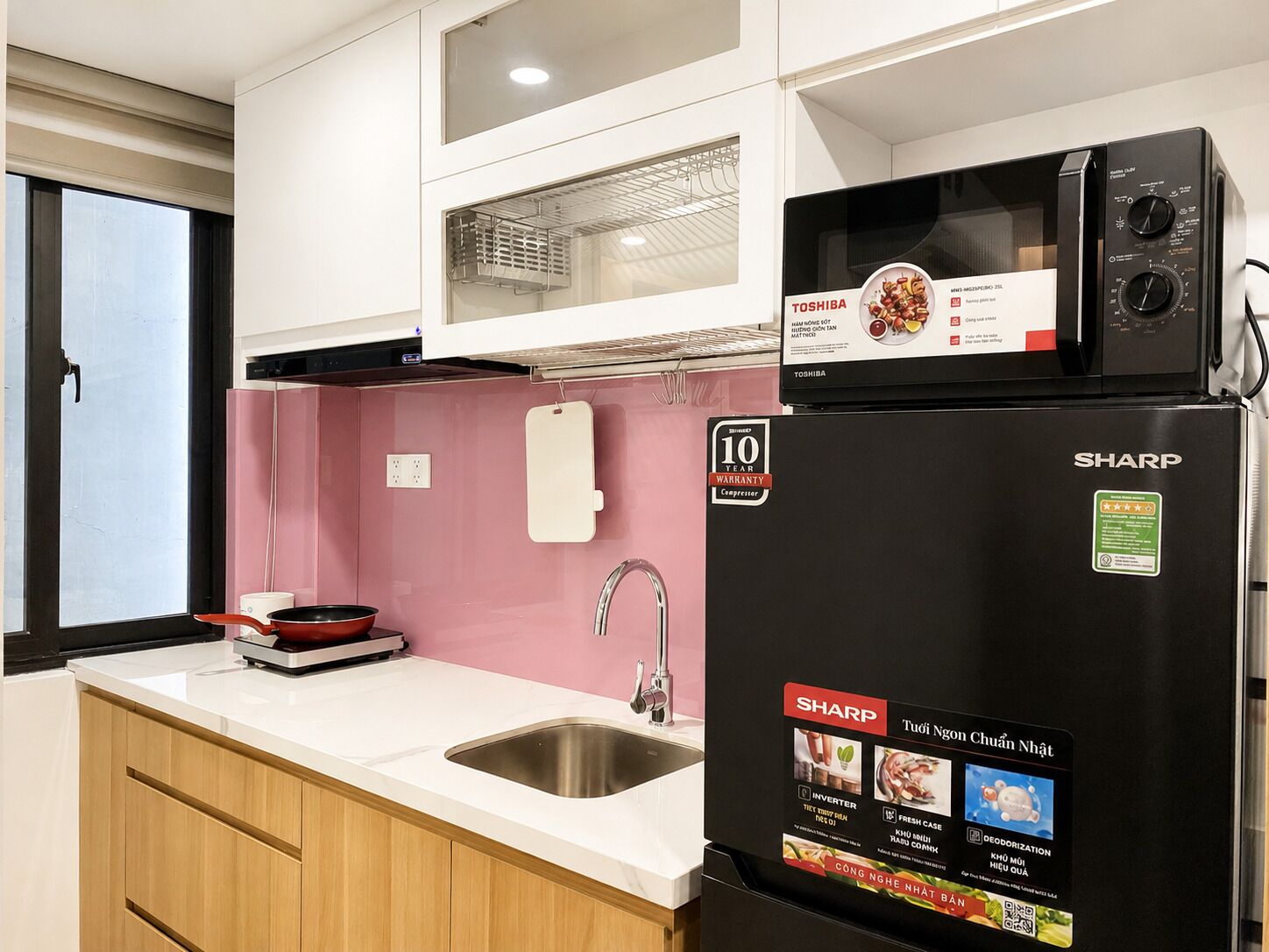 Cocina compacta con refrigerador, microondas y lavamanos.