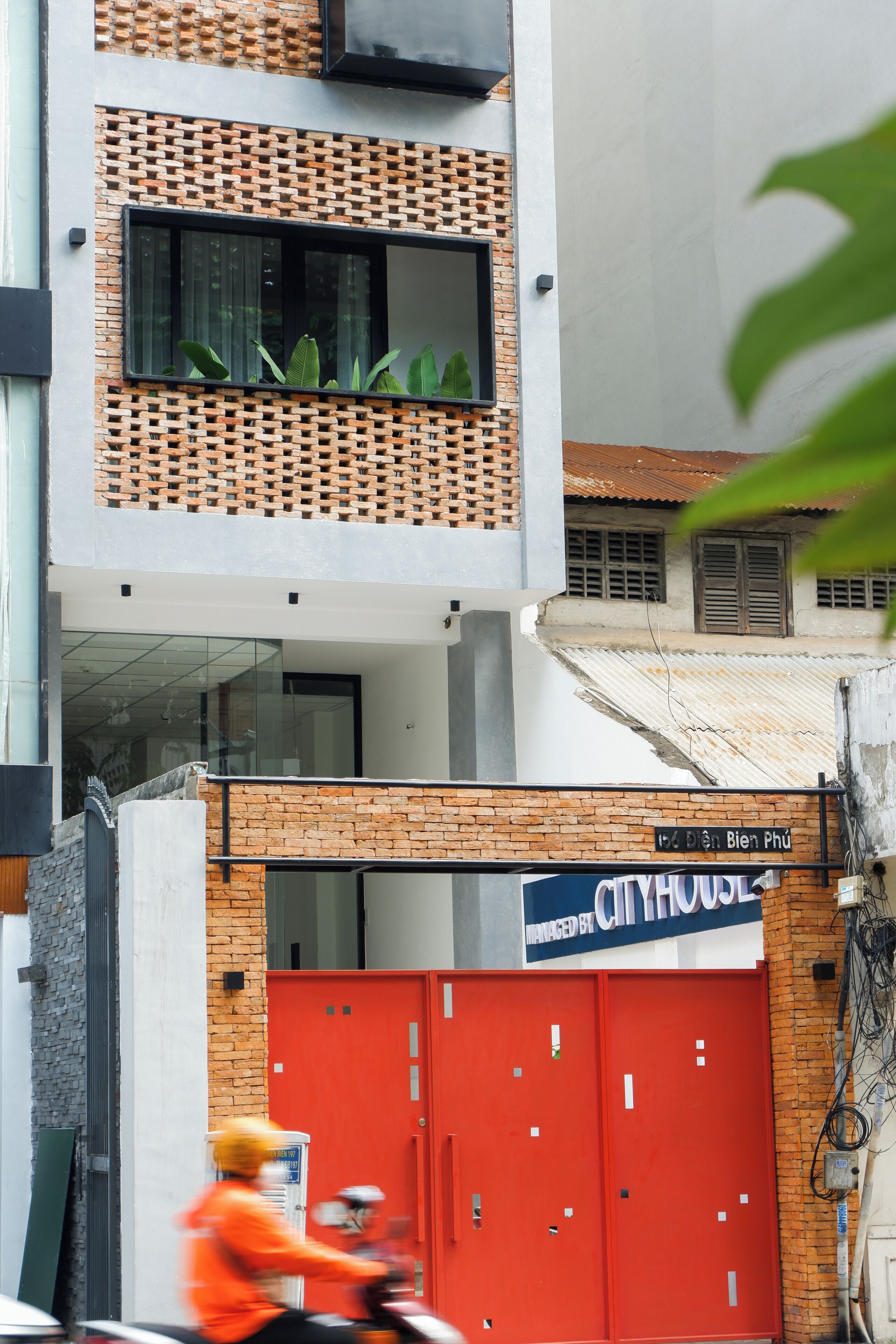Un edificio con fachada de ladrillo, un letrero que dice 'CITYHOUSE' y una verja roja.