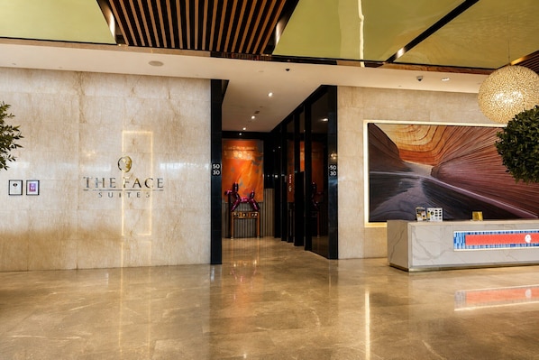 A hotel lobby with a reception desk, a large wall mural, and a modern ceiling design. - Platinum Suites KLCC by Moonlight (Kuala Lumpur)