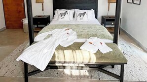 Una cama con dosel, un cabecero, dos mesitas de noche y un ventilador de techo.