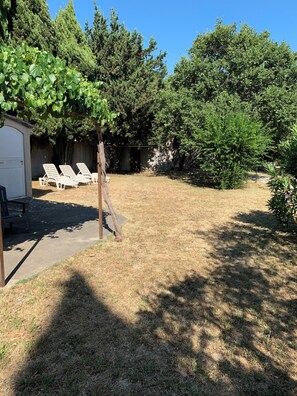A backyard with a covered seating area, a shed, and a variety of trees. - Cottage in the Vineyards (Roquemaure)