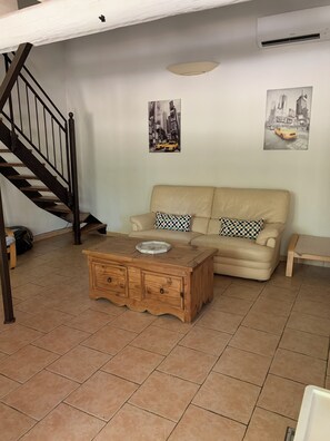 A living room with a staircase, a sofa, a coffee table, and two wall-mounted pictures. - Cottage in the Vineyards (Roquemaure)