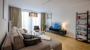 Una sala de estar moderna con un sofá, una mesa de centro, un televisor y una estantería.