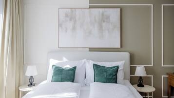 A hotel room with a large bed, two bedside tables with lamps, a painting on the wall, and a view of the outdoors.