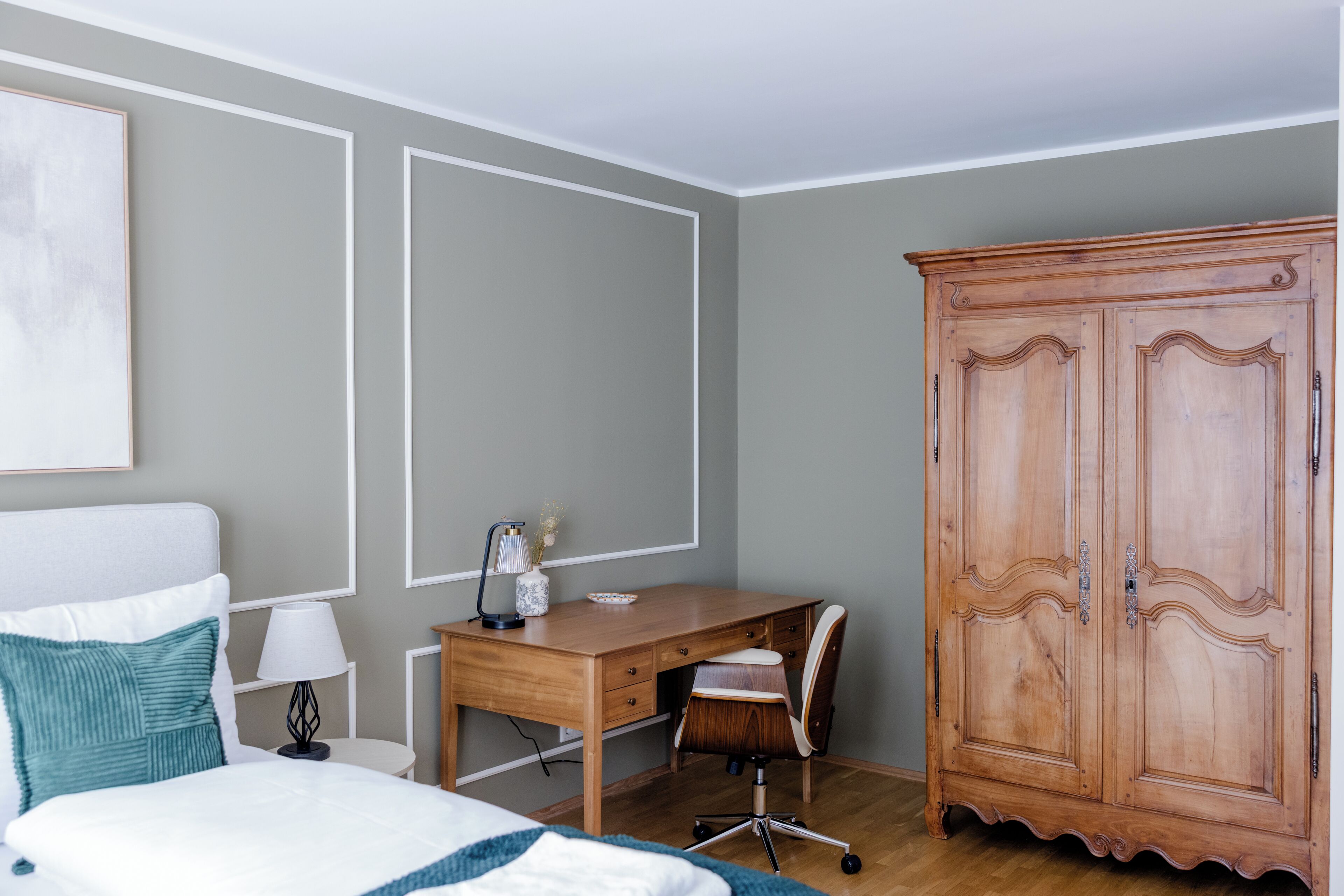 Un dormitorio con cama, escritorio, silla, armario y lámpara.