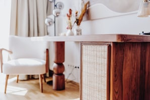Un interior moderno con una mesa de comedor de madera, una silla blanca y una mesita auxiliar de mimbre.