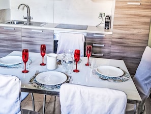 Eine moderne Küche mit Esstisch für sechs Personen, ausgestattet mit einer Edelstahlspüle, Holzschränken und einem eingebauten Backofen.