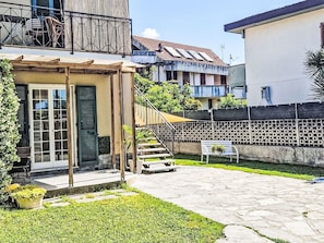 Ein Wohngebäude mit überdachter Terrasse, einer Treppe und einem Garten.