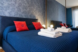 A modern bedroom with a large bed, red pillows, and a blue bedspread. - VivimiHome Suite Casa Degli Specchi (Milano)