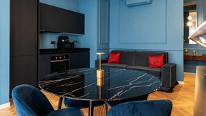 Eine moderne Küche mit schwarzen Schränken, einem schwarzen Marmortisch und einem blauen Sofa mit roten Kissen.