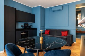 Eine moderne Küche mit schwarzen Schränken, einem schwarzen Marmortisch und einem blauen Sofa mit roten Kissen.