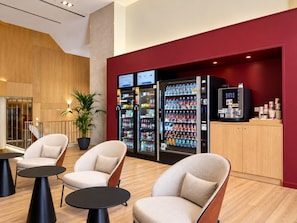 En modern entréhall med sittplatser, försäljningsautomater och en reception.