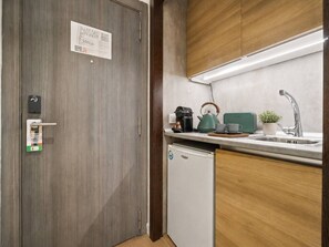 A compact kitchen with a built-in dishwasher, a coffee maker, a kettle, and a toaster on the countertop. - Studio Apartment Adapted for People with Limited Mobility · Retiro (Madrid)