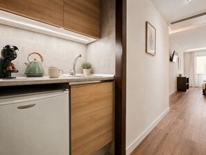 A modern kitchen with a built-in refrigerator, a kettle, and a small potted plant on the countertop. - Studio Apartment Adapted for People with Limited Mobility · Retiro (Madrid)