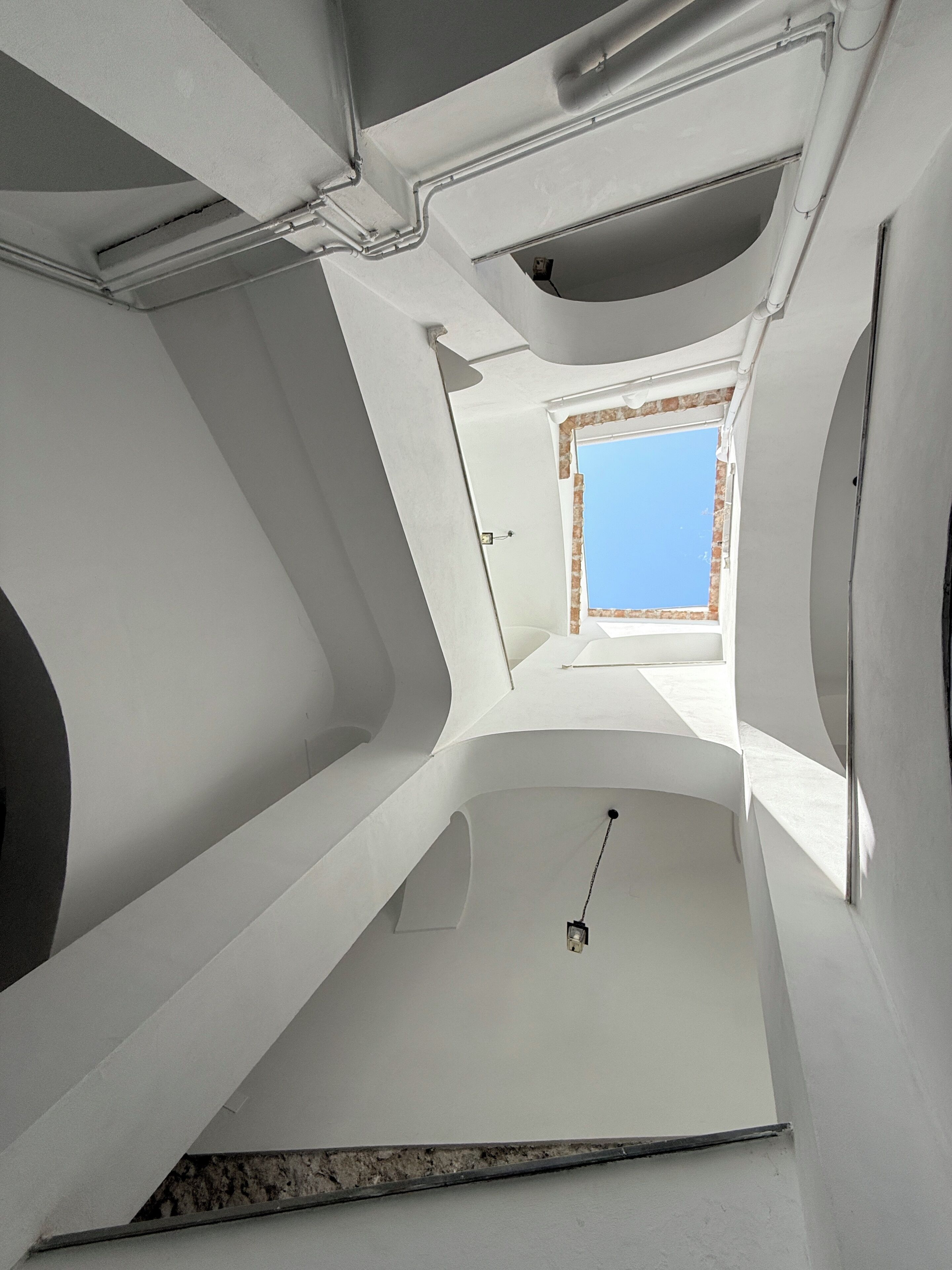 Un intérieur moderne avec une verrière, des murs blancs et une porte visible donnant sur un espace extérieur.