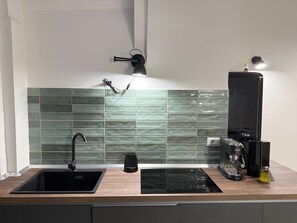 A modern kitchen with a black sink, a coffee machine, and a wall-mounted light. - Seafonia - Apartment in the Heart of Salerno (Salerno)